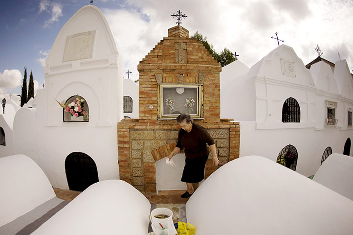 All saints day: A woman clean's the grave of a relative in the cemetery , Spain