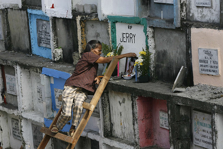 All saints day: A mother uses a ladder to reach her son's tomb in Manila