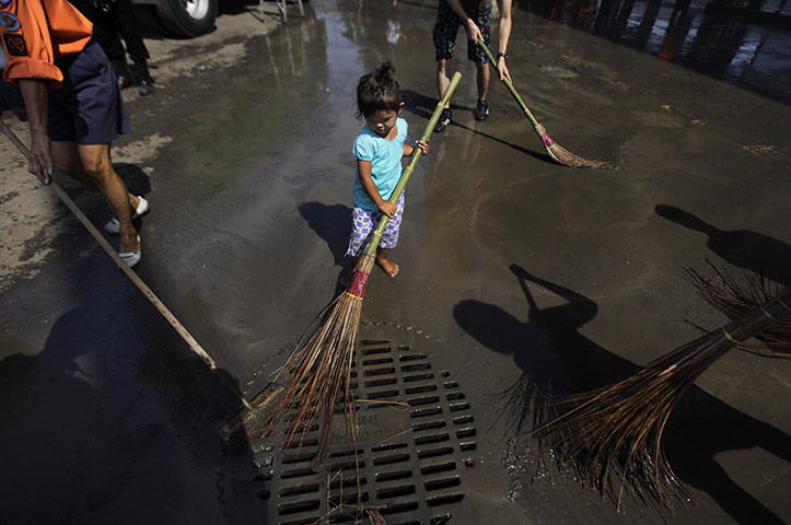24 hours in pictures: A girl joins up as volunteers sweef after floodwaters receded in Bangkok