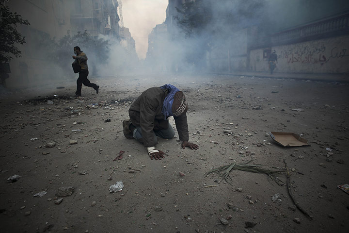 24 hours in pictures: Cairo, Egypt: A protester overcome with tear gas inhalation kneels