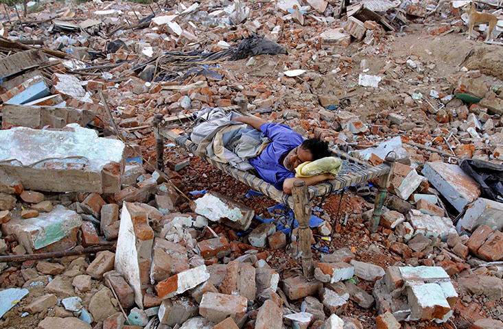 24 hours in pictures: Ahmedabad, India: An Indian man sleeps in the rubble of his demolished hut 