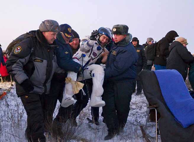 Soyuz landing Kazakhstan : Ground personnel carry ISS crew member Russian cosmonaut Sergei Volkov