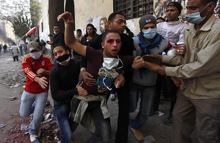 Egypt protests continue: Protesters carry a wounded man during clashes with the Egyptian riot police