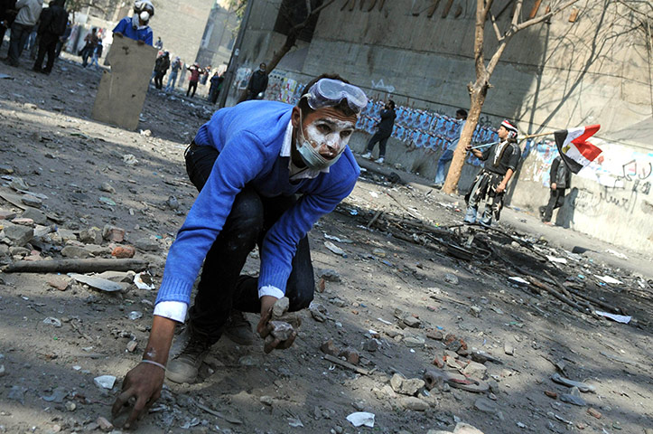 Egypt protests day 5: An Egyptian protester picks up rocks during clashes with riot police