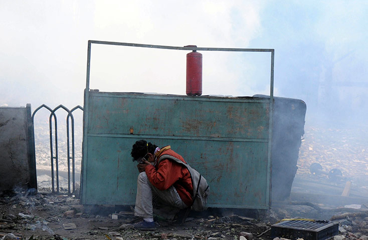 Egypt protests day 5: An Egyptian protesters takes cover during clashes with riot police