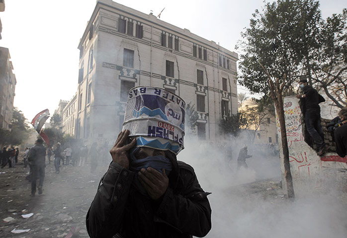 Egypt protests day 5: An Egyptian protester protects his face from tear gas using a tin can