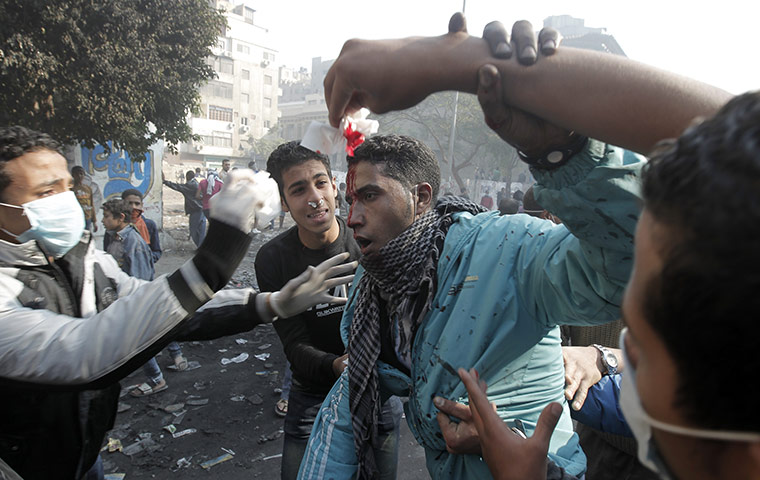 Egypt protests day 5: An injured Egyptian protester is helped away during clashes