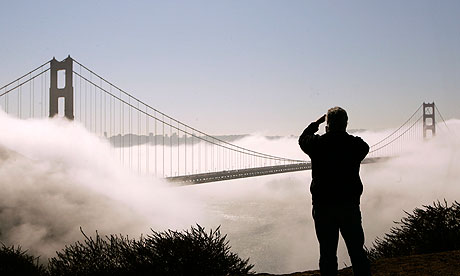 Man takes photographs of Golden Gate Bridge shrouded in fog in San Francisco