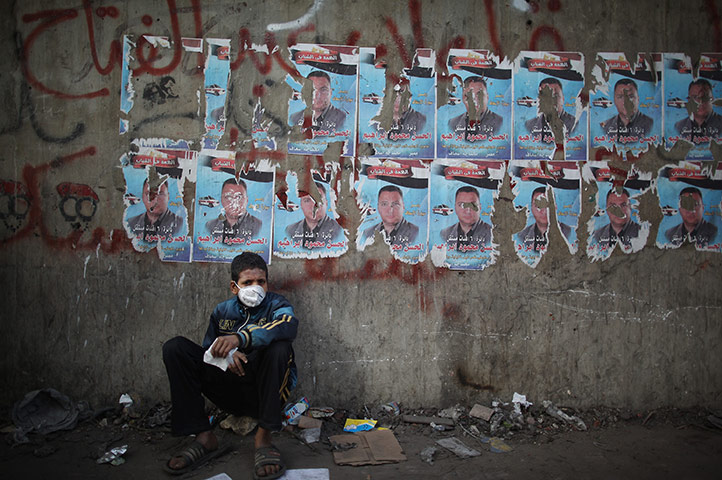 Egypt protests day 5: A boy wearing a face mask sits in Mohammed Mahmoud St after police withdrew