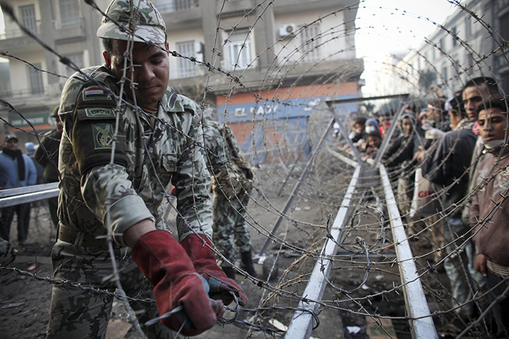 Egypt protests day 6: An Egyptian soldier helps to put a barbed wire barricade in place