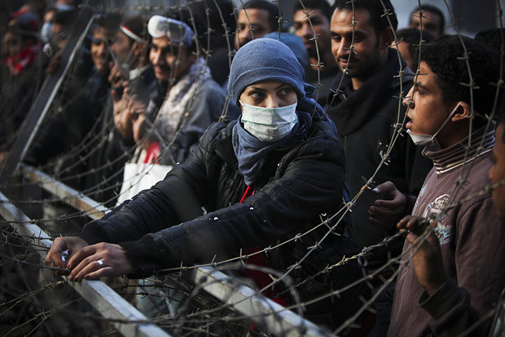 Egypt protests day 6: A woman protester attempts to dismantle a barbed wire barricade