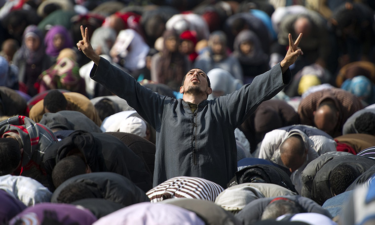 Tahrir Square: A man flashes the V-sign for victory during Friday prayers