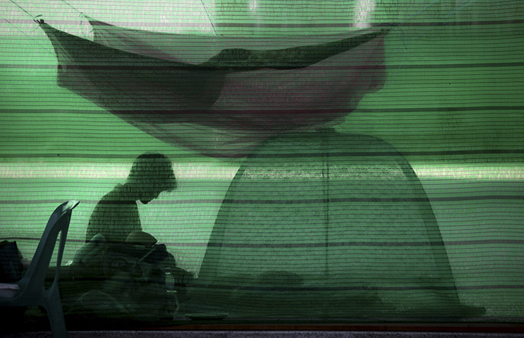 24 hours: A Thai flood victim sits under a mosquito at a relief centre