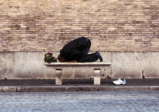 24 hours: A street vendor selling roses prays on a bench in downtown Rome
