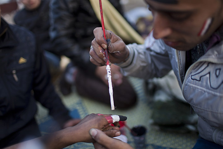 Tahrir Square: A protester paints the finger of another protester