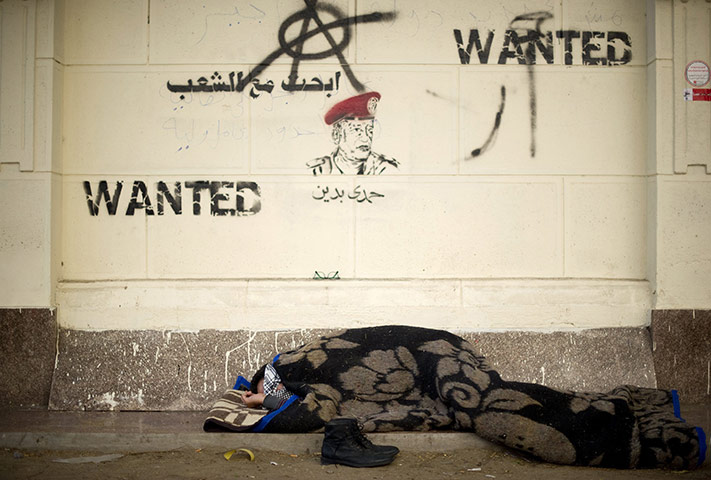 Tahrir Square: An Egyptian demonstrator sleeps under graffiti