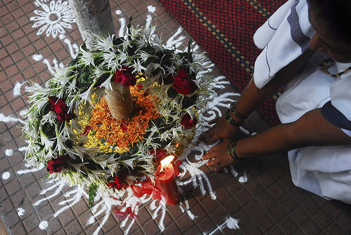 24 hours in pictures: Mumbai, India: A woman offers prayers at a wreath
