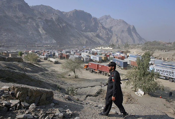 Pakistan NATO raids: A policeman keeps guard along a hilltop overlooking gridlocked trucks