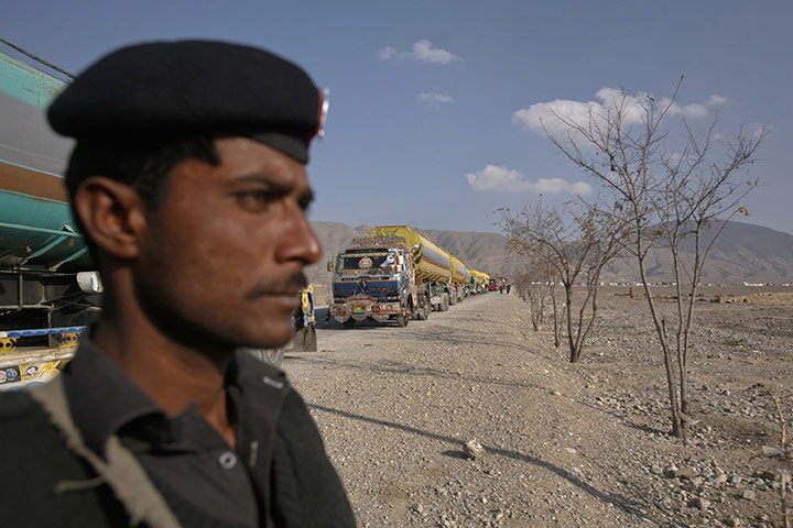 Pakistan NATO raids: A policeman stands guard near trucks as they lined up near Quetta
