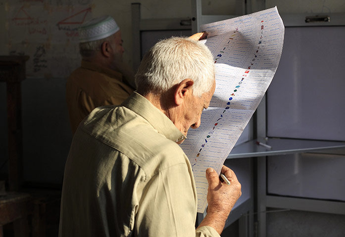 Egypt elections: An old man reads a ballot paper before casting his vote