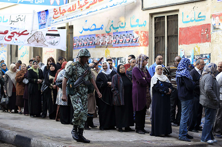 Egypt elections: An Egyptian soldier guards as Egyptians wait to cast their votes 