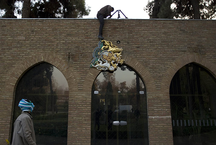 Tehran embassy: A protester removes the emblem of the British embassy in Tehran
