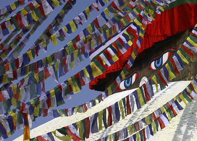FTA: Navesh Chitrakar : An eye of Lord Buddha is seen behind prayer flags at Boudhanath Stupa 