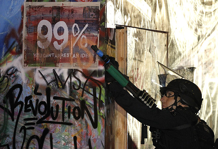 Occupy LA evictions: A Los Angeles police officer points his weapon to demonstrators