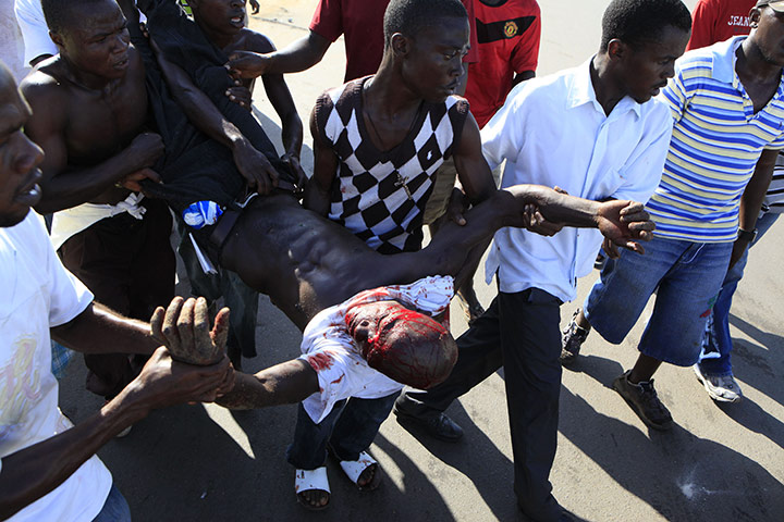 Liberia violence: Opposition party supporters carry a wounded man during clashes