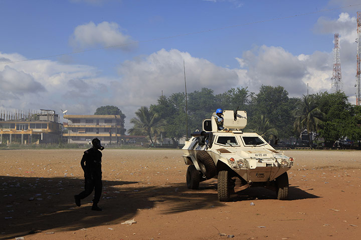 Liberia violence: A Liberian policeman in a gas mask walks past a UN armoured vehicle