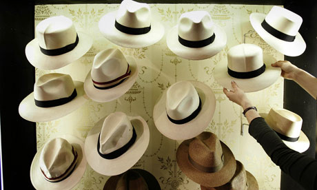 A sales assistant adjusts hats at James Lock & Co hat shop in London
