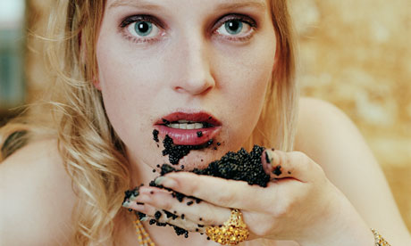 Young woman holding handful of caviar to mouth small young titties