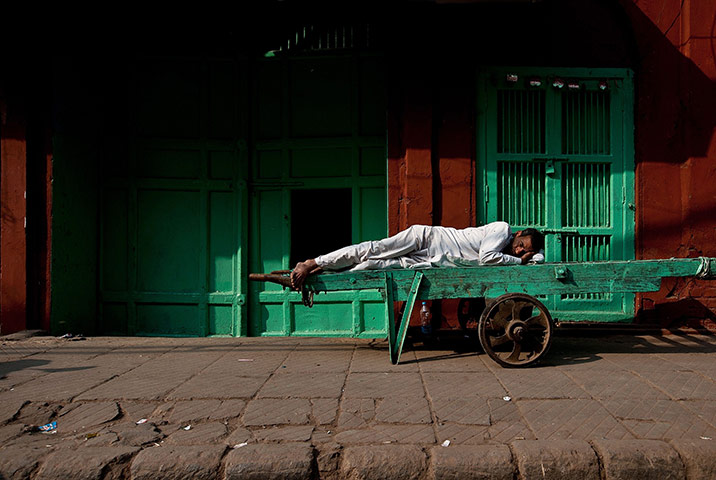 24 hours in pictures: An Indian labourer takes a nap in front of closed shops