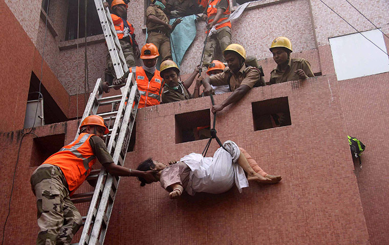 24 hours in pictures: Rescue workers evacuate a woman after a fire engulfed Amri hospital