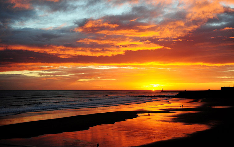 24 hours in pictures: People walk on the beach during sunrise over Tynemouth Longsands