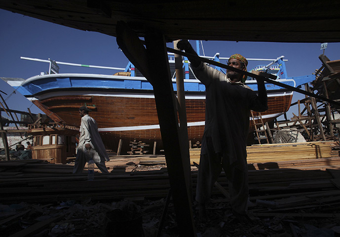 24 hours: Karachi, Pakistan: A man assembles the hull of a wooden boat at a shipyard