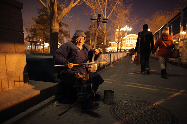 24 hours: Beijing, China: A blind man plays an erhu instrument as he busks
