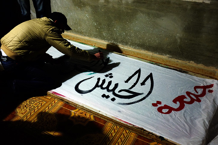 Syria: Activists paint anti-goverment slogans on banners in Benish 
