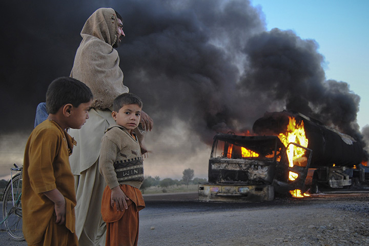 24 hours: Bolan district, Pakistan: Boys watch fuel trucks which were set ablaze