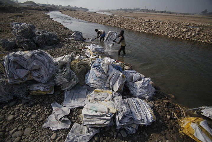24 hours: Jammu, India: Indian labourers wash emptied cement bags at the Tawi River