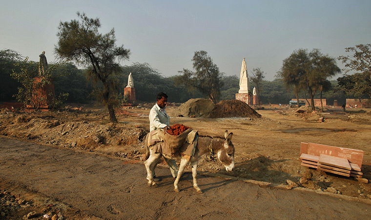24 hours: New Delhi, India: An Indian labourer carries bricks for construction