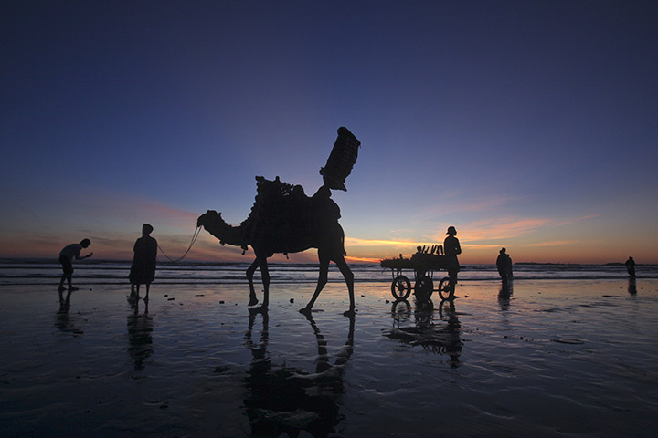 24 hours: Karachi, Pakistan: A man sells roasted corn from his cart on the beach