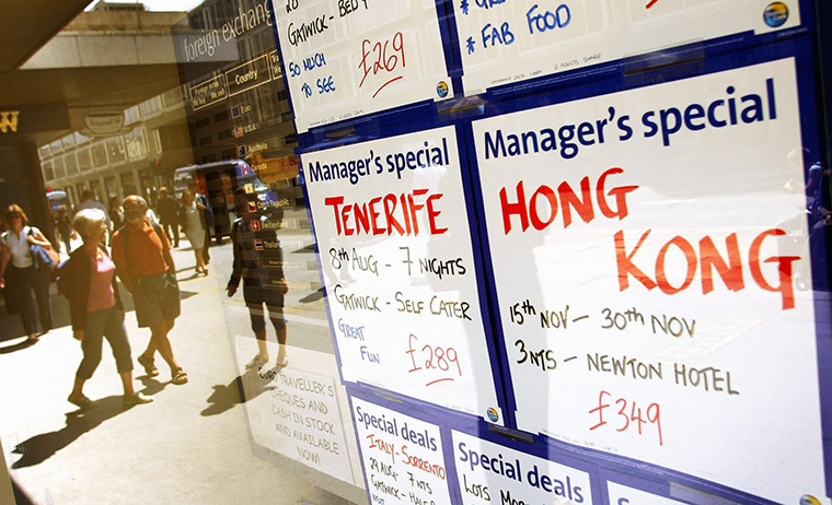 Thomas Cook: People walk past a window display of travel agency Thomas Cook