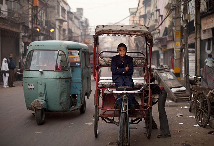 24 hours in pictures: New Delhi, India: A boy waits for a rickshaw driver to make an adjustment