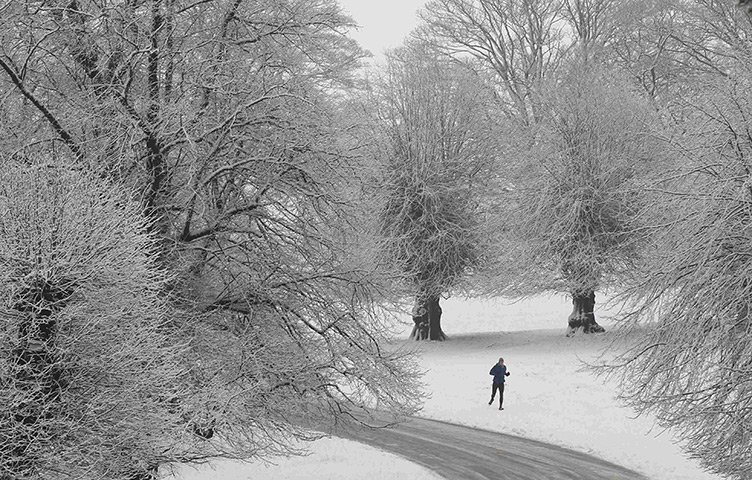 UK Weather: A man runs in the snow at Lyme Park near Manchester