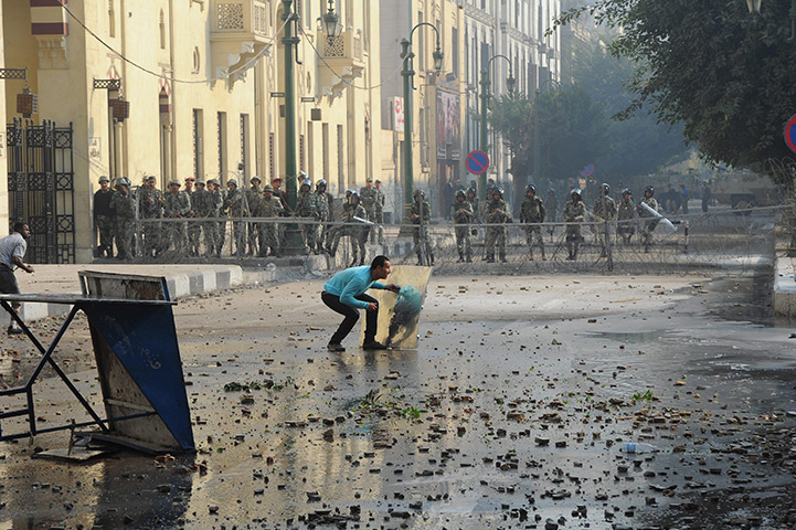 Tahrir Square clashes: An Egyptian protester takes cover during clashes