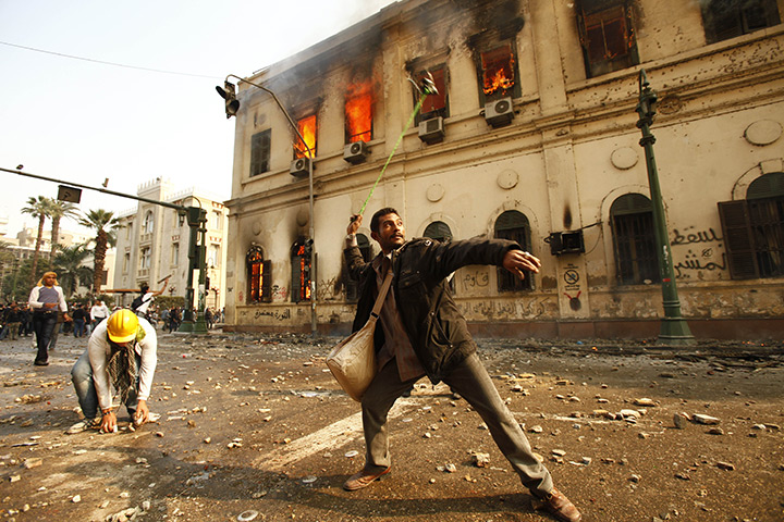 Tahrir Square clashes: A protestor hurls stones during clashes with security forces
