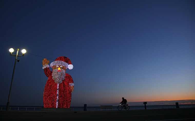 24hours in pictures: A cyclist rides past an illuminated Santa Claus, Nice