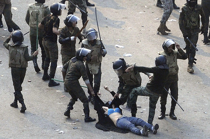 24hours in pictures: Egyptian army soldiers arrest a female protester at Tahrir Square