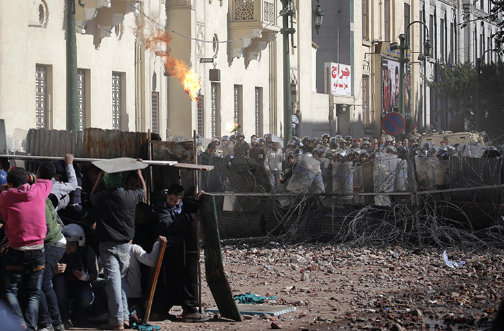Cairo clashes: Egyptians take cover throwing a fire bomb toward army soldiers 